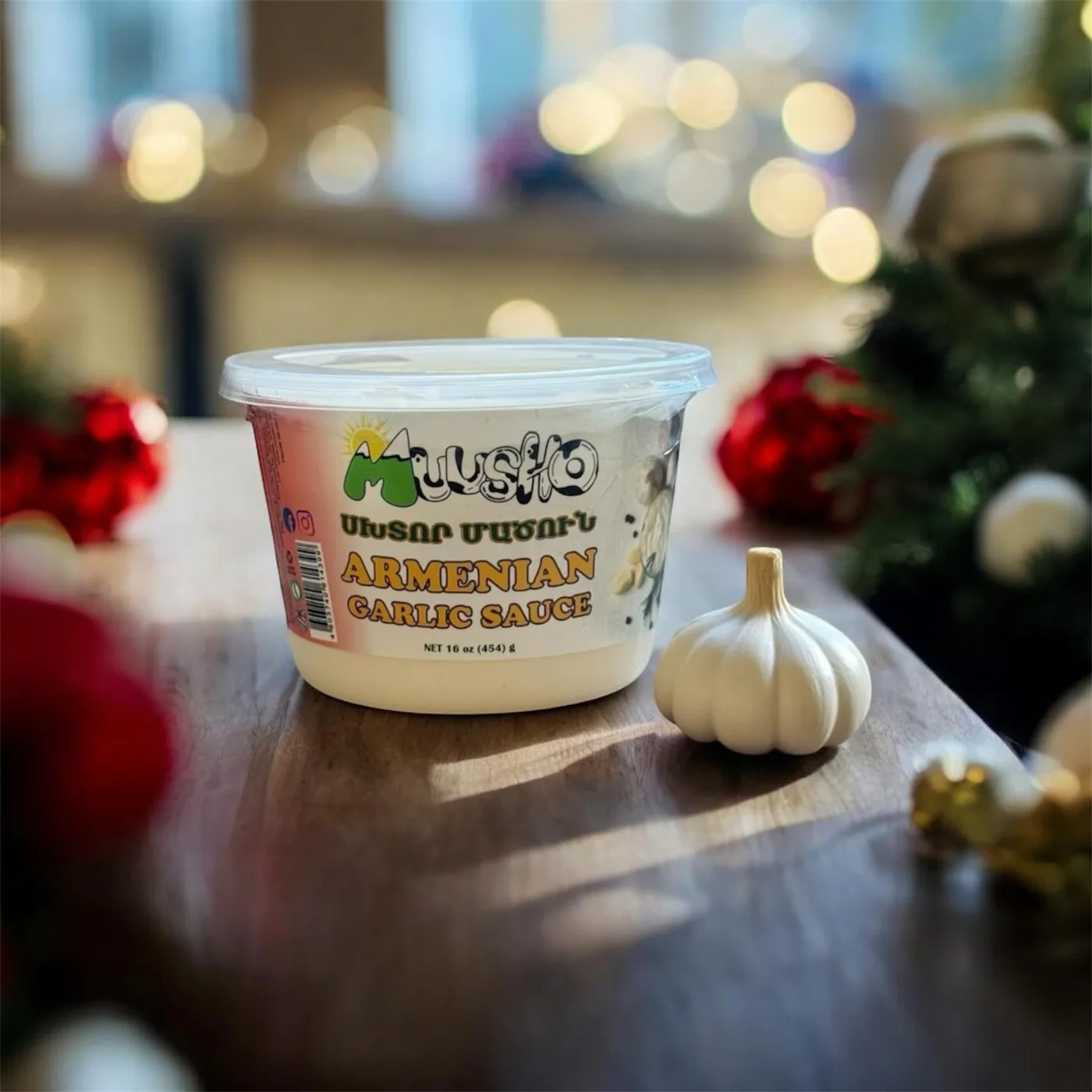 A tub of Muusho Armenian garlic yogurt and a garlic bulb on a festive table